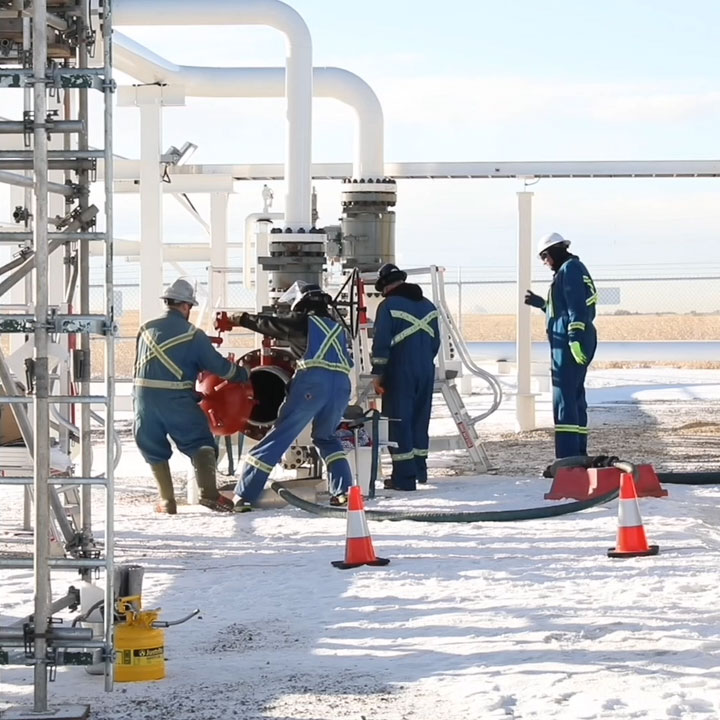 Un groupe de quatre techniciens se prépare à lancer un outil à l'intérieur du pipeline à une station de pipeline en conditions hivernales.