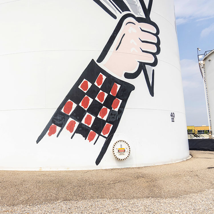 Réservoir de carburant avec une peinture d’un bras tenant un chapeau.