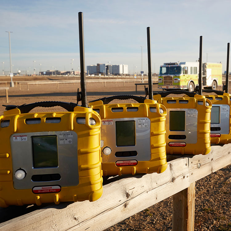 Des dispositifs de communication d'urgence alignés le long d'une clôture, avec un camion de pompiers visible en arrière-plan.