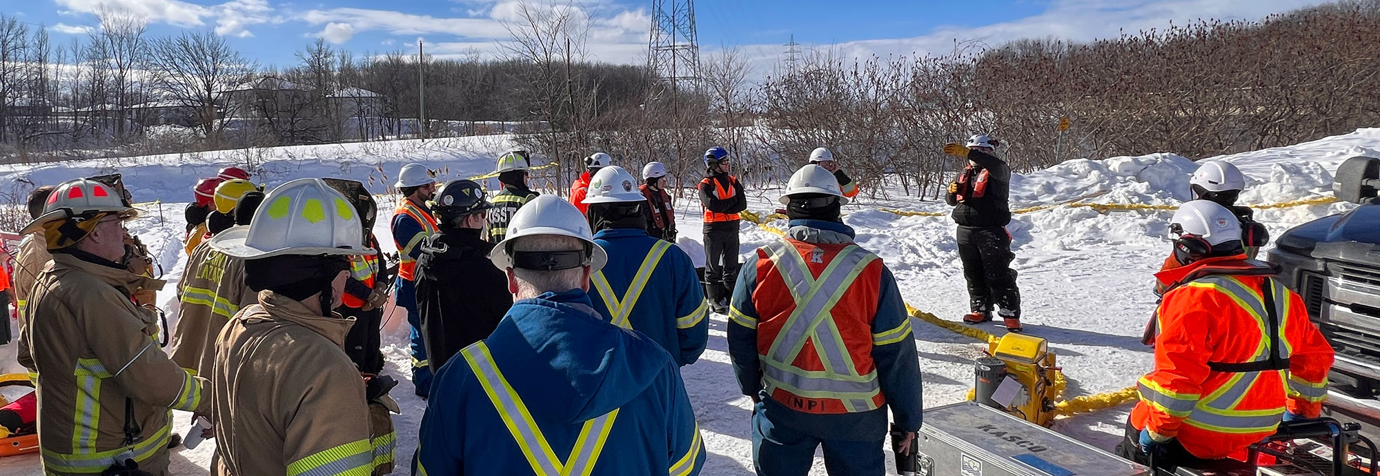 Un groupe de premiers intervenants et de techniciens de pipelines sont informés avant de déployer une flèche au-dessus d'une rivière gelée lors d'un exercice d'entraînement au Québec.